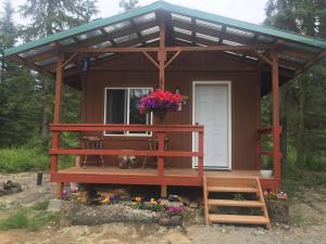 a small cabin with a porch in the woods at Whispering Woods AK Cabins in Kasilof