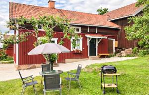 une table avec des chaises et un parasol devant un bâtiment rouge dans l'établissement Cozy Home In Rttvik With Kitchen, à Rättvik