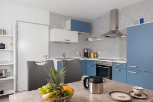 a kitchen with blue cabinets and a bowl of fruit on a table at WiLoMa in Baden-Baden