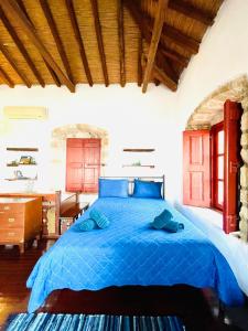 Schlafzimmer mit einem blauen Bett und einem Schreibtisch in der Unterkunft vecchia casa in Monemvasia