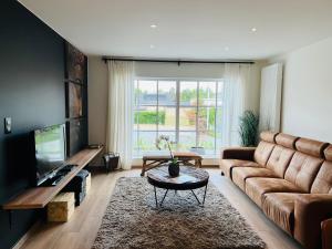 uma sala de estar com um sofá e uma televisão em Vakantiewoning De Winning em Aan de Wolfsberg