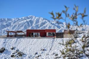a red house in front of a snow covered mountain at Potre casas de montaña in Potrerillos