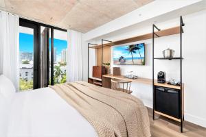 a bedroom with a bed and a desk and windows at Urbanica Fifth in Miami Beach