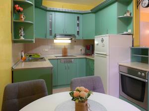 a kitchen with green cabinets and a table with chairs at MB Apartments in Jagodina