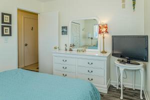 a bedroom with a dresser with a television and a mirror at Sea Spray Place in Kure Beach
