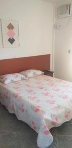 um quarto com uma cama com um edredão rosa e branco em Pousada das Casuarinas em Saquarema