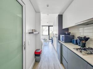 a kitchen with white cabinets and a long hallway at Cozy, Work Station, Wi-Fi, Patio in Cape Town
