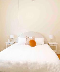 a white bed with a orange pillow on top of it at BIRCHWOOD ON BRIDGE in Tanunda