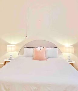 a white bed with two pink pillows on it at BIRCHWOOD ON BRIDGE in Tanunda