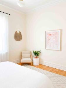 a white bedroom with a white bed and a chair at BIRCHWOOD ON BRIDGE in Tanunda