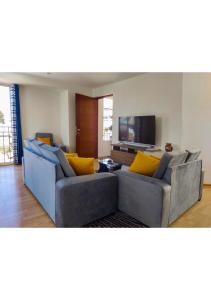 a living room with two couches and a flat screen tv at Buena Vista Apartment in Cusco