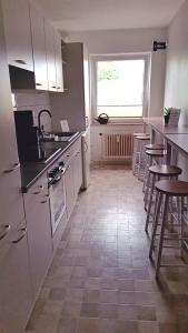 a kitchen with white cabinets and tables and a window at Dithmarscher Haus in Marne