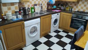 a kitchen with a washing machine and a sink and a checkered floor at 119 the shaftesbury in Barking