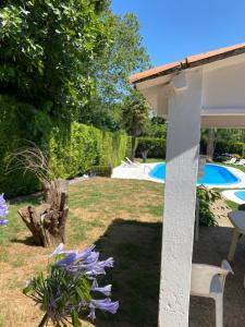 a garden with a table and purple flowers and a pool at Agradable chalet rústico in Cambre