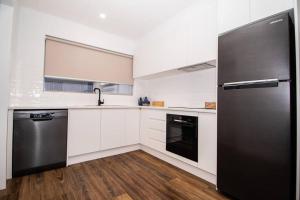 una cucina con armadietti bianchi e frigorifero nero di Willow Court Unit 2 a Broken Hill