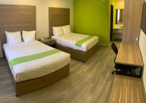 エルモシージョにあるHotel Bugambiliaのベッド2台とデスクが備わるホテルルームです。