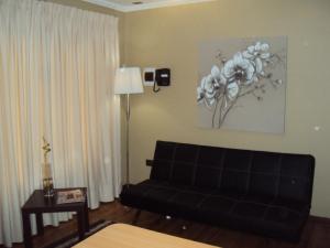 una sala de estar con un sofá negro y una pintura en la pared en Apart Hotel Cancura, en Chillán