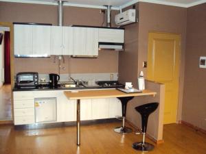 a kitchen with white cabinets and a wooden counter top at Apart Hotel Cancura in Chillán