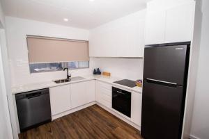 uma cozinha com armários brancos e um frigorífico preto em Willow Court Unit 4 em Broken Hill