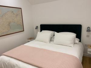 ein Bett mit weißen Kissen und einer Karte an der Wand in der Unterkunft The Garden House in Penzance