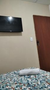 a bedroom with a bed with a flat screen tv on the wall at Hospedagem ensolarada in Japaratinga