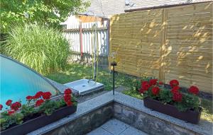 a car parked next to a swimming pool with red flowers at 2 Bedroom Lovely Home In Badersleben in Badersleben
