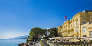 a yellow building next to a body of water at Hotel Kvarner - Liburnia in Opatija