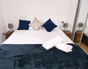 una camera da letto con un grande letto bianco con cuscini blu di Lovely 1 Bedroom Apartment - Bham City Centre a Birmingham