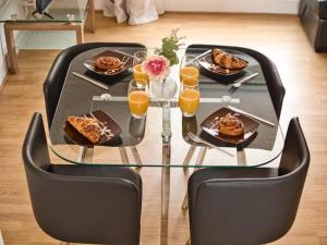 Lovely 1 Bedroom Apartment - Bham City Centre في برمنغهام: طاولة زجاجية مع أطباق من الطعام وكؤوس من عصير البرتقال