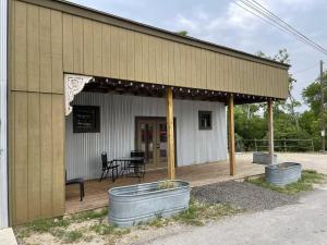 a building with a porch with a table and two buckets at Trails End Retreat in Bandera