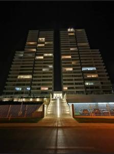 Deux grands bâtiments sont éclairés la nuit dans l'établissement Hermoso Departamento en Con Con Edificio Mares de Montemar, à Concón