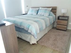 - un lit avec une couette bleue et blanche dans une chambre dans l'établissement Hermoso Departamento en Con Con Edificio Mares de Montemar, à Concón