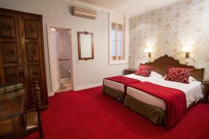 a hotel room with two beds with red sheets at Hotel Dom Sancho I in Lisbon