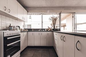 a kitchen with white cabinets and a large window at Bay Properties Pacific Sun in Yamba