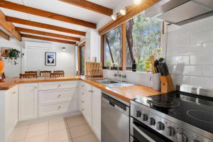 een keuken met witte kasten en een fornuis met oven bij Fern Cottage in Wye River