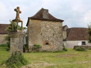 una vieja iglesia de piedra con una cruz en un campo en Gîte Monsac, 2 pièces, 2 personnes - FR-1-616-101, en Monsac