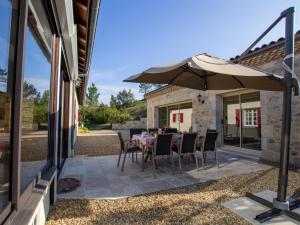 a patio with a table and an umbrella at Maison de charme avec piscine privée, salle de sport proche de Bergerac et Périgueux - FR-1-616-132 in Villamblard