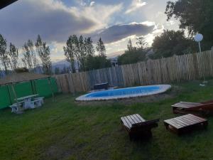 a backyard with a pool and picnic tables and a fence at cabañas inti in Ullún