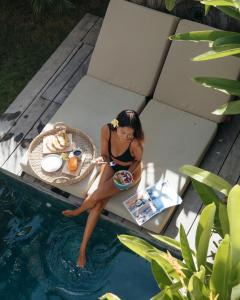 a woman sitting on a table next to a swimming pool at Kalea Villas in Kuta Lombok