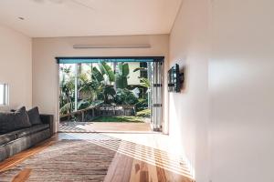 a living room with a couch and a large glass door at Bay Properties The Big Chill in Yamba +6 photos