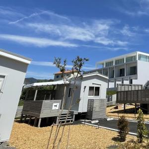 un edificio bianco con balcone e una casa di Necoana Glamping富士山景BBQトレーラーヴィラ a Fujikawaguchiko