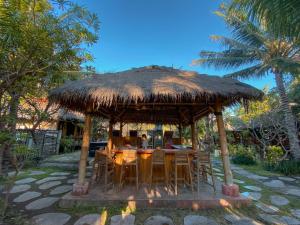 a table and chairs under a straw hut at Sejuk Cottages in Gili Air