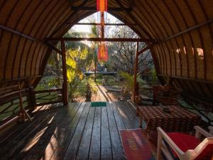eine hölzerne Veranda einer Hütte mit einem Bett und einem Kronleuchter in der Unterkunft Sejuk Cottages in Gili Air