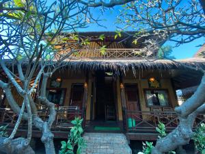 a house with a thatched roof with a porch at Sejuk Cottages in Gili Air