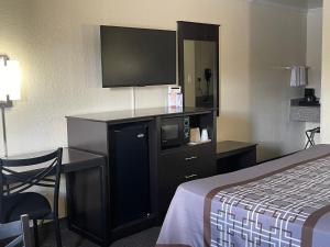 a hotel room with a bed and a flat screen tv at Lufkin Inn in Lufkin