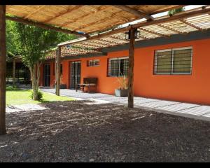 Una vista exterior de una casa con una pared naranja. en Cabañas Casa fuerte, en San Rafael