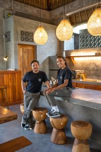 two men sitting on a counter in a restaurant at Villa Amantes Bingin in Uluwatu