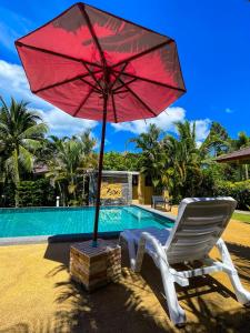a red umbrella and a chair next to a pool at Mingmongkol Resort in Koh Samui