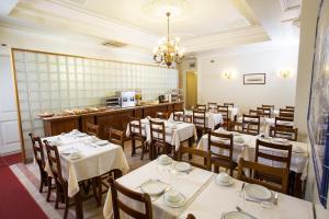 a restaurant with white tables and chairs and a counter at Hotel Dom Sancho I in Lisbon