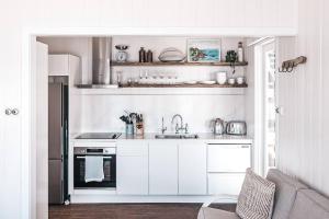 a kitchen with white cabinets and a sink at Bay Properties Beach House Studio in Yamba